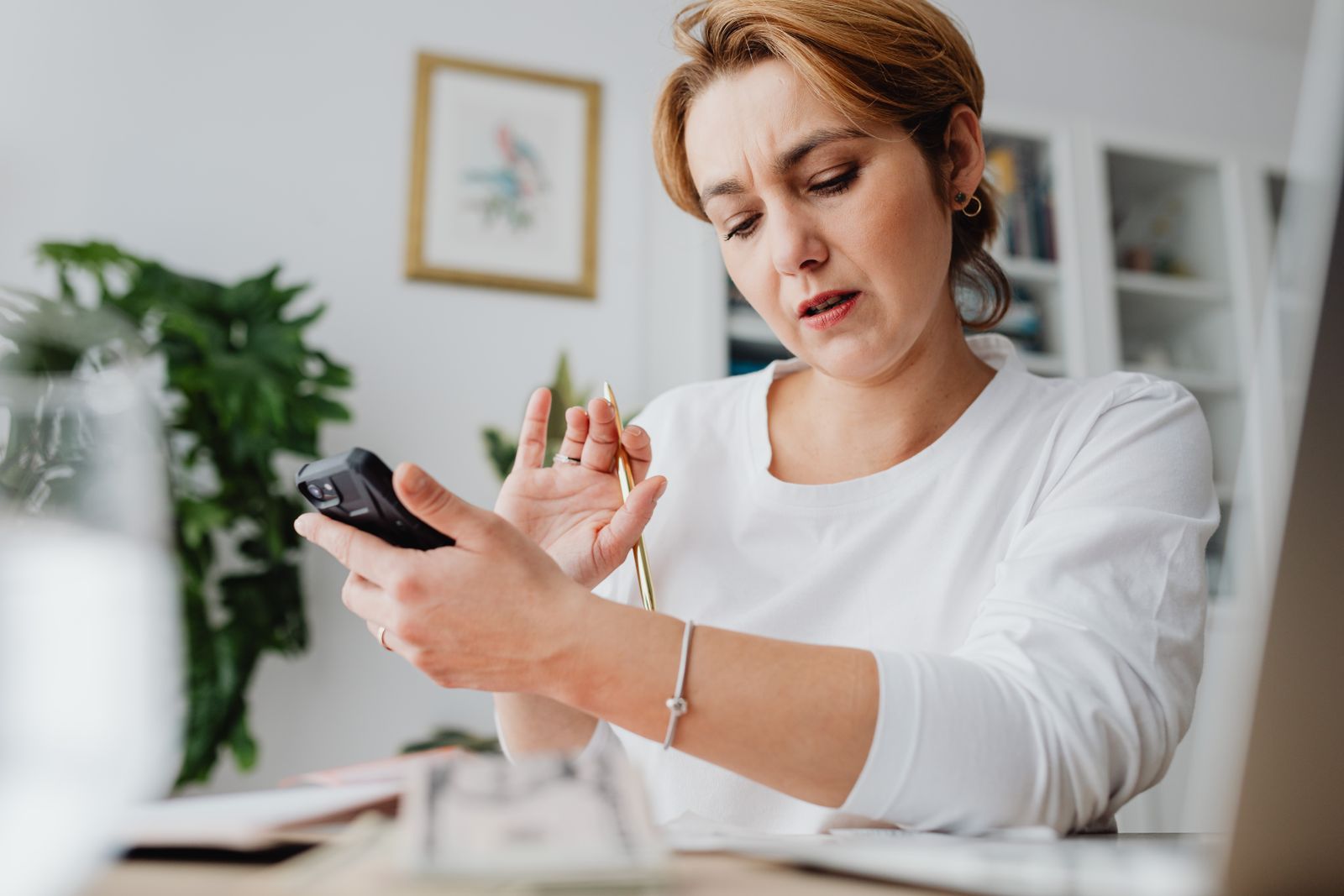 A woman using a smartphone beside a laptop