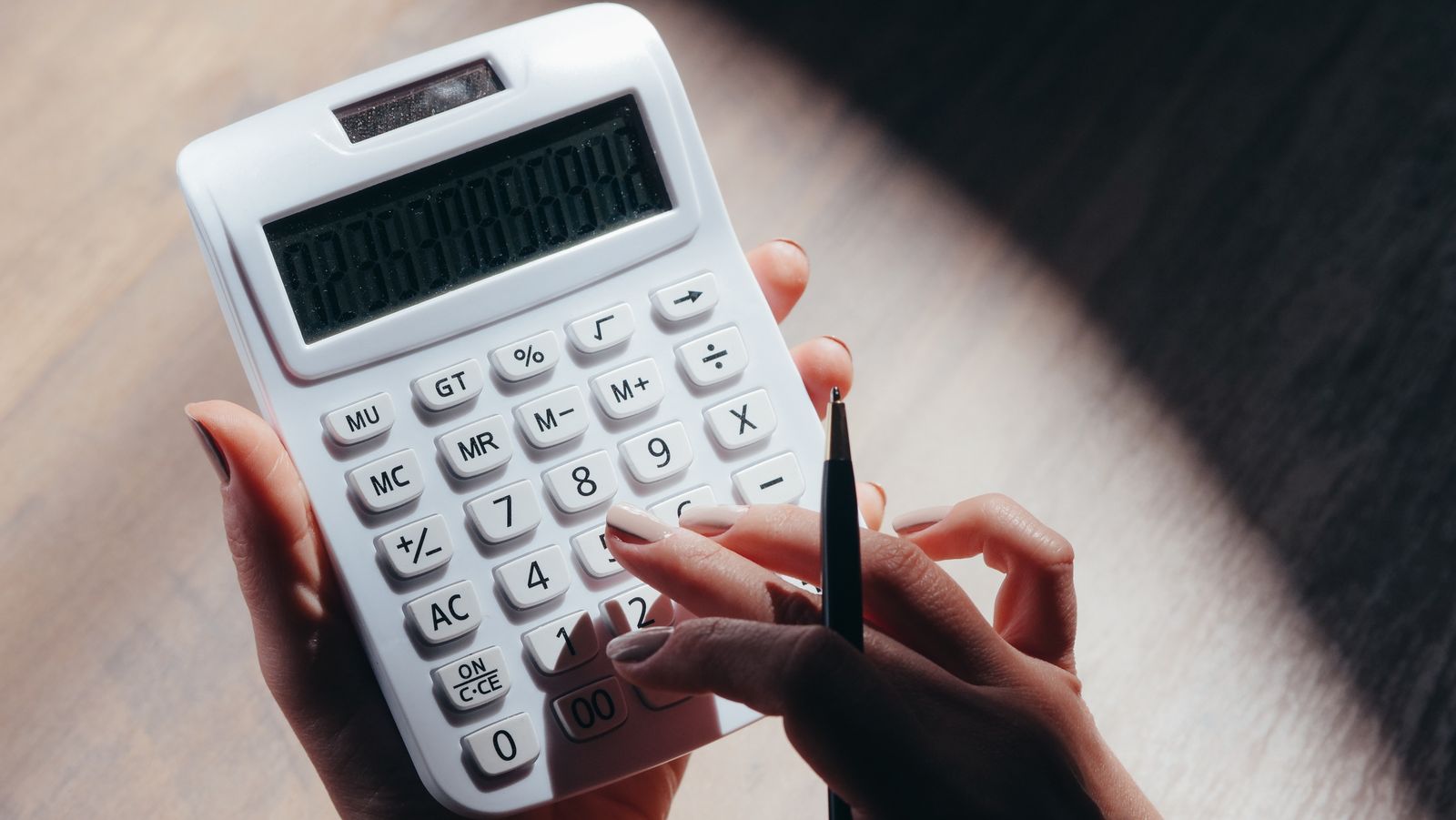 Hands pressing buttons on a white calculator
