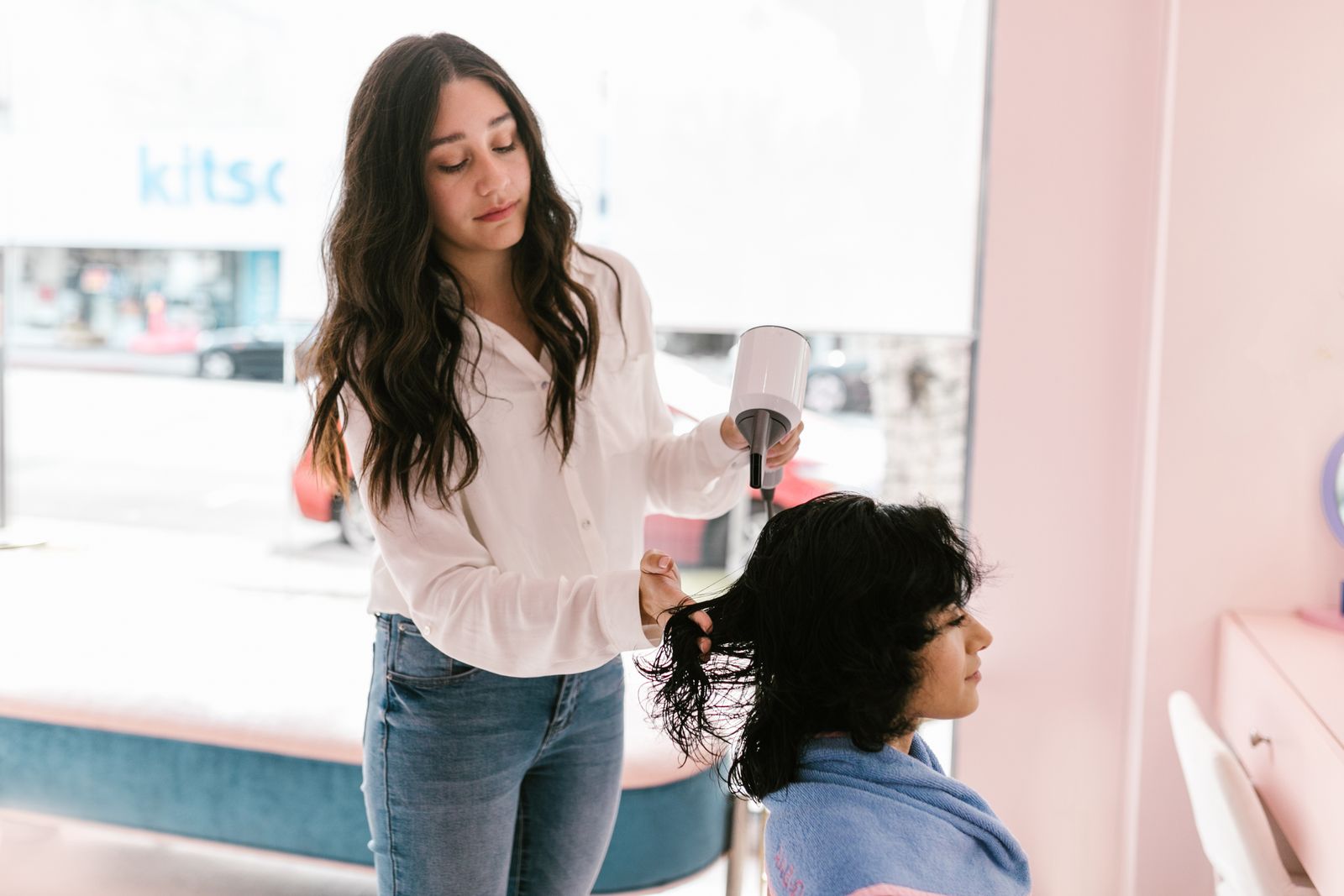 A hairdresser using a hairdryer while styling a client’s hair